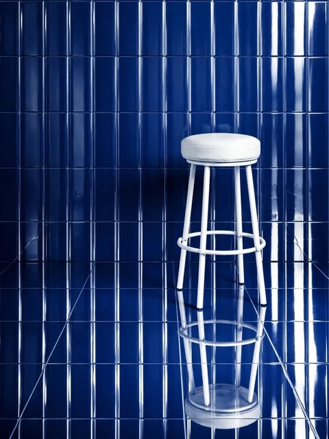 Taburete blanco y reflejos sobre azulejos azules